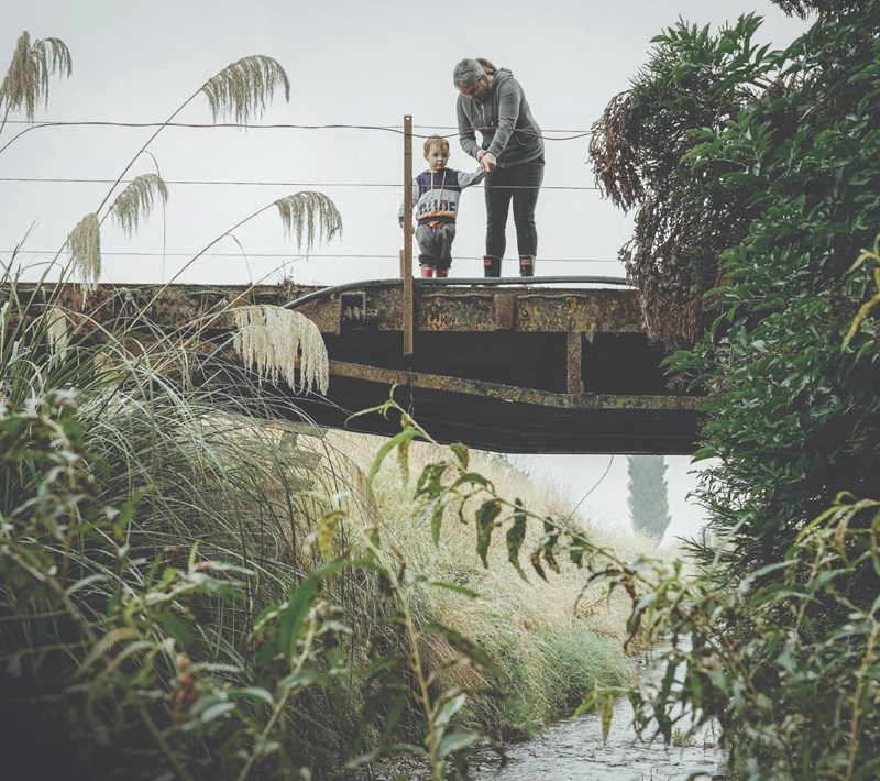 Jolene Germann and son standing on bridge above stream.