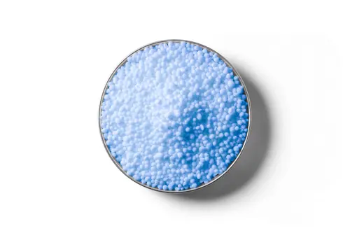 Light blue Flexi N (nBPT) coated urea fertiliser granules in a round dish